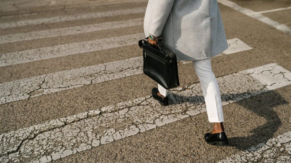 From above male businessman in stylish clothes with briefcase walking on zebra crossing