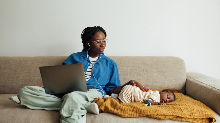 woman working from home on the couch while her baby boy sleeping next to her