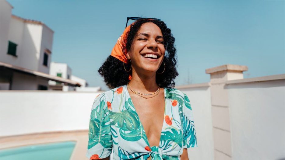 a young happy woman laughing with a beautiful smile outdoors, during a sunny summer day.