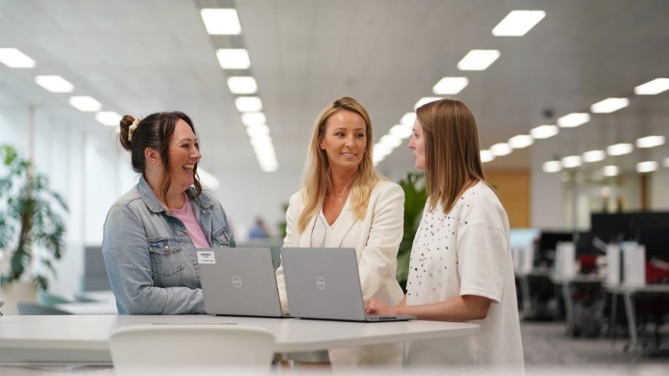 Female holding and looking at tablet in office area with large plant