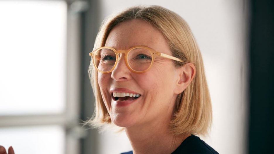 close up of a happy smiling woman wearing glasses with natural light from a window
