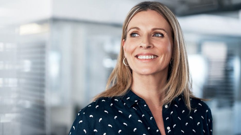 Professional woman smiling in office area with soft focus background