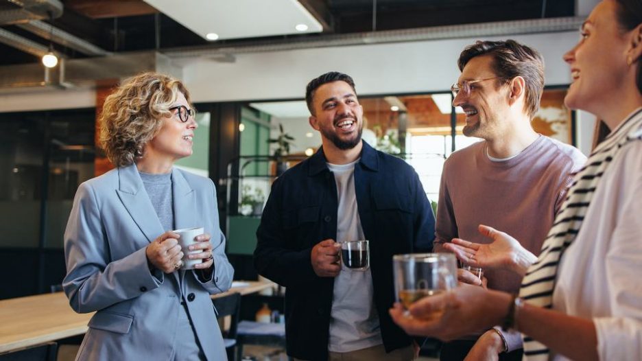 group of men and women in office chatting over coffee