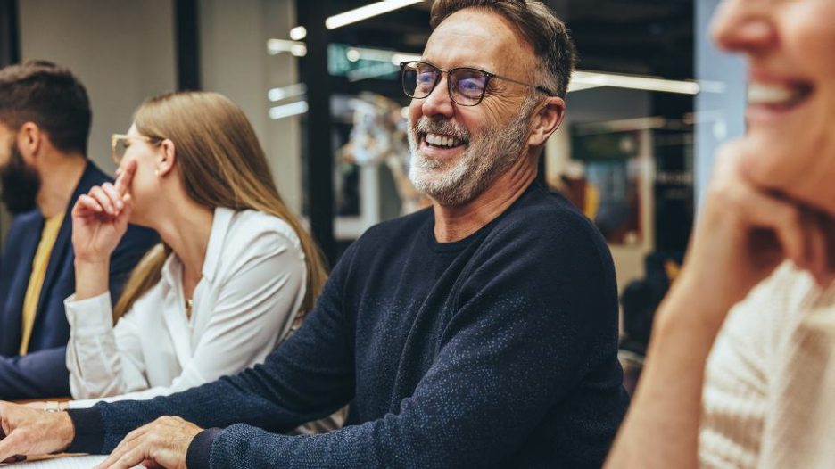 Laughing male with glasses and beard in office meeting