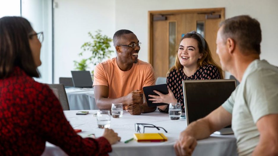 Male and females in meeting with laptop and tablet