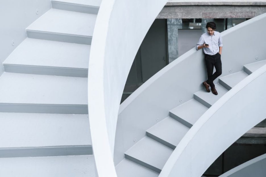 Young Asian businessman using smartphone on stairs