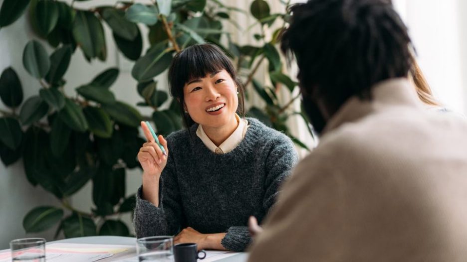 two women having a meeting and smiling while they look at a tablet