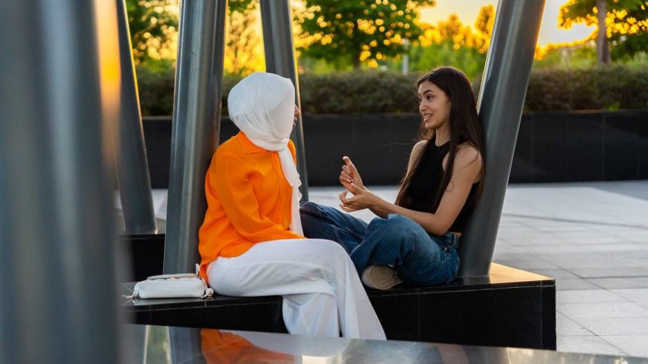 Two Muslim Women Having A Conversation Outdoors on a sunny afternoon