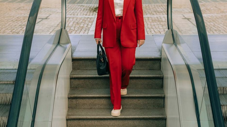 woman in red office suit walking down the stairs