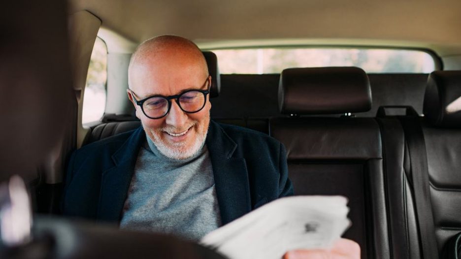 businessman sitting in the car, reading newspapers while traveling to work