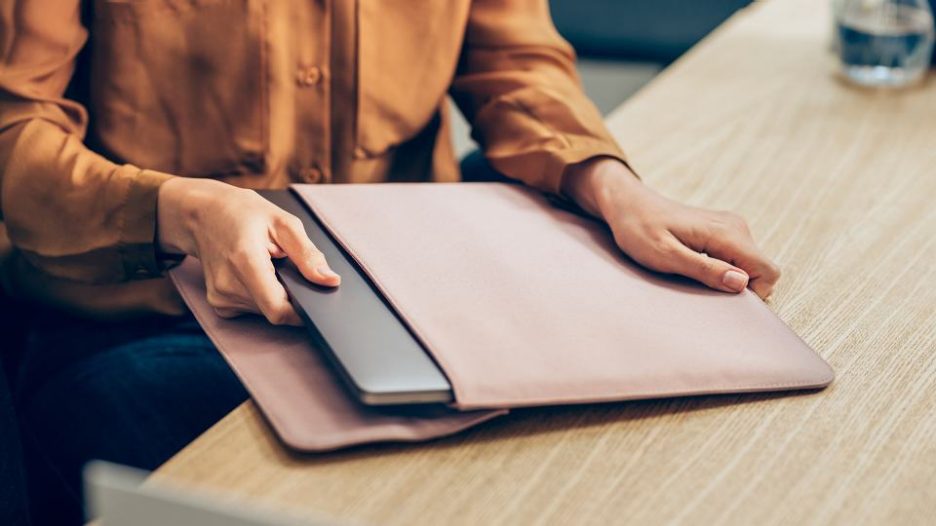 female cropped below shoulders removing laptop from case