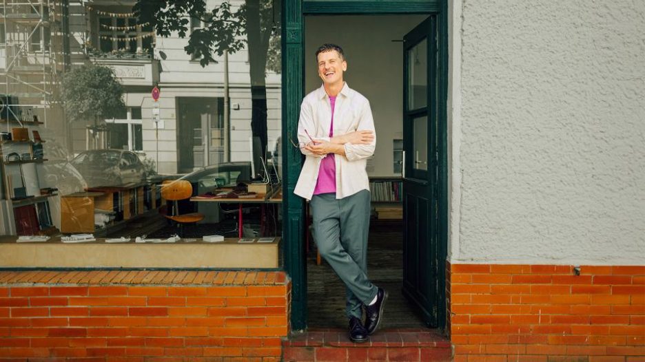 smiling man standing in shop doorway 